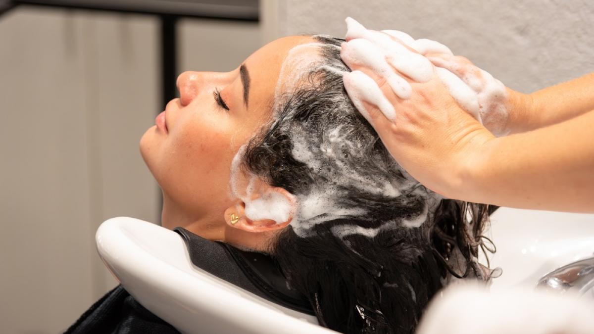 femeie la salon in timp ce este spalata pe cap