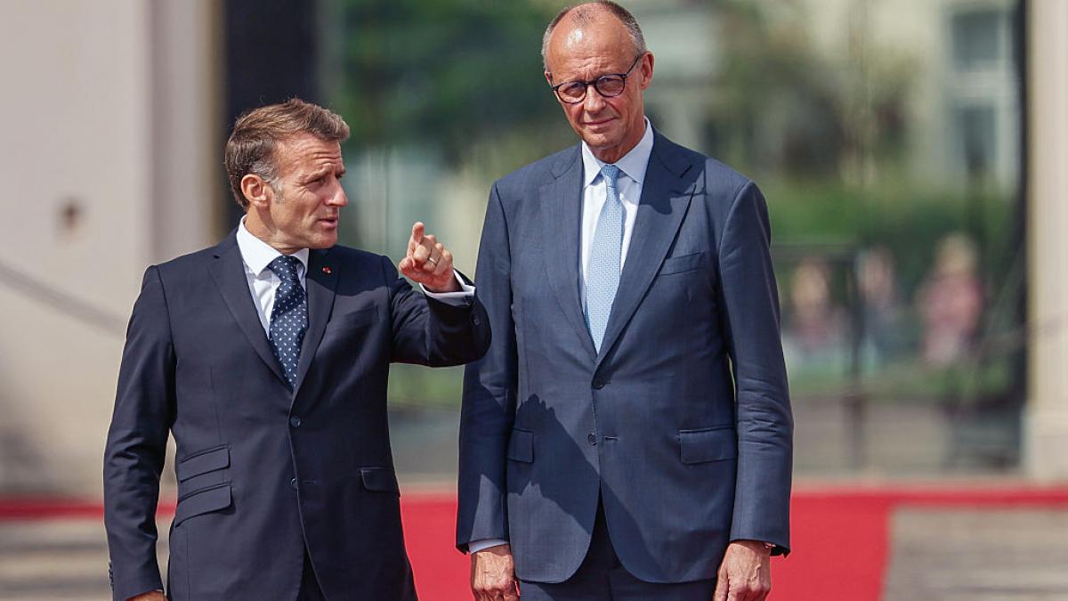 Macron îi arată ceva unui Merz zâmbitor