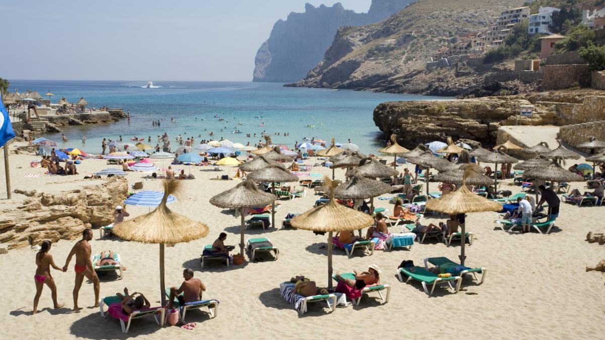 turisti pe plaja cu umbrele si sezlonguri