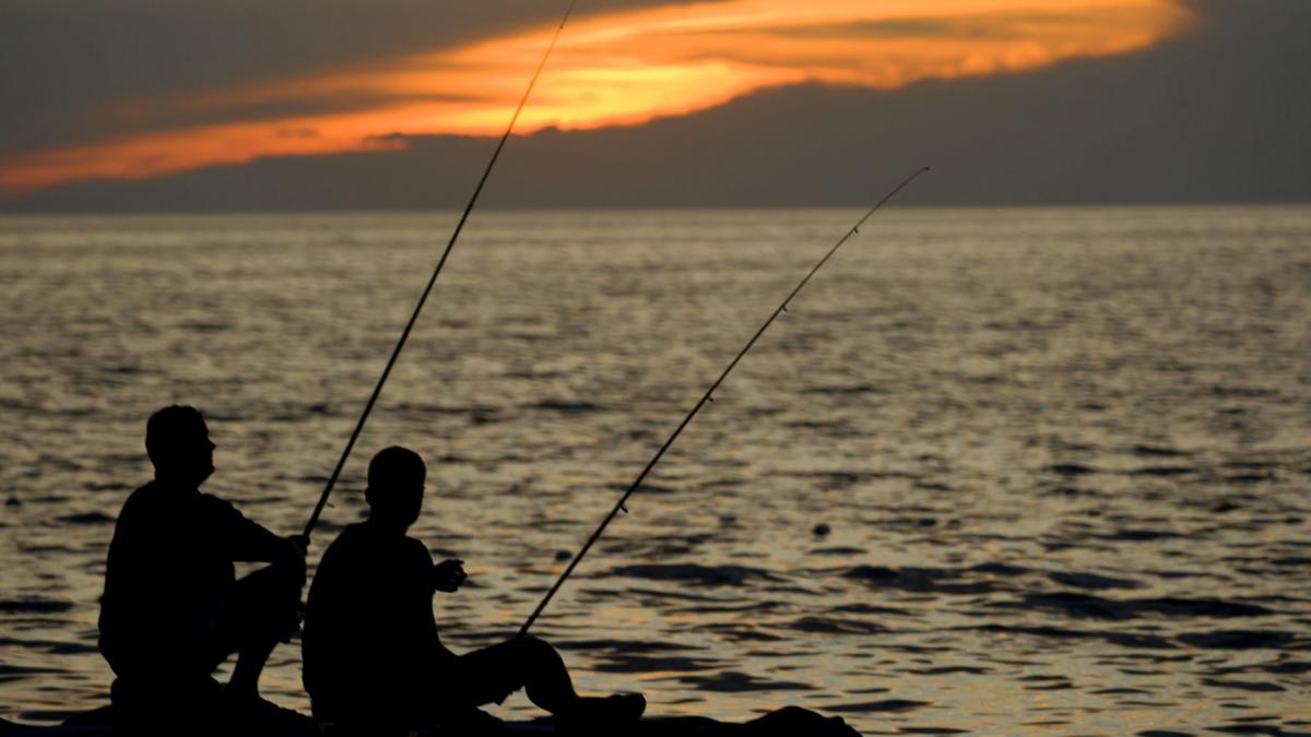 doi pescari care pescuiesc la apus