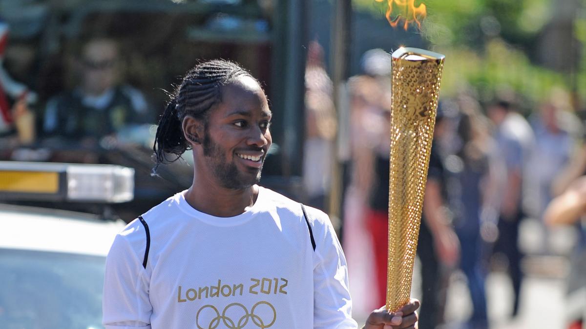 poza in care apare Jason Arday a purtat Flacăra Olimpică în cadrul etapei din 2012 a ștafetei torței, pe traseul dintre Sutton și Merton, la Londra. Sursa foto: Hepta
