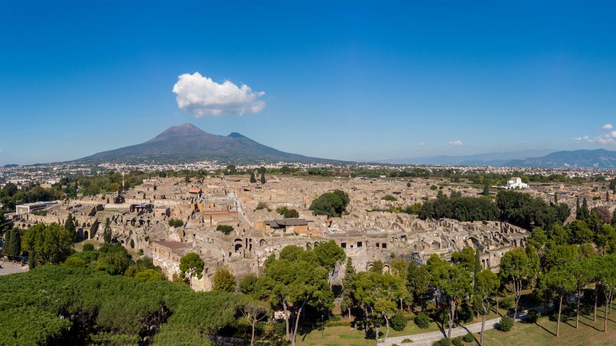 imagine de sus cu ruinele pompeiului si muntele vezuviu in departare