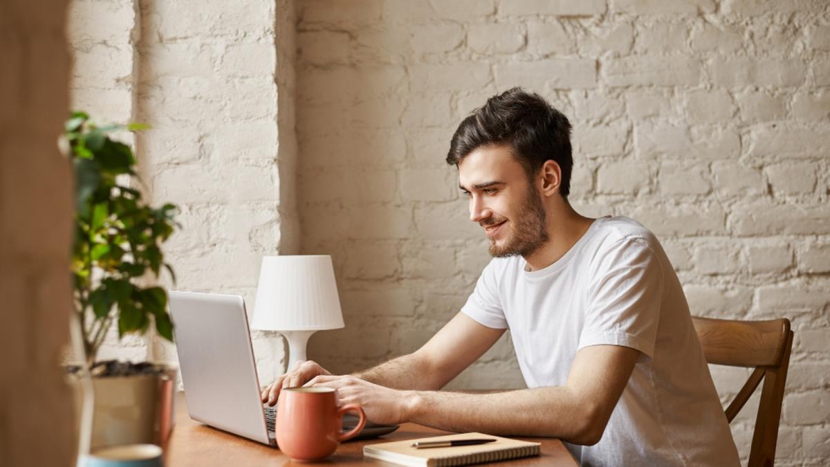 barbat la masa cu un laptop in fata