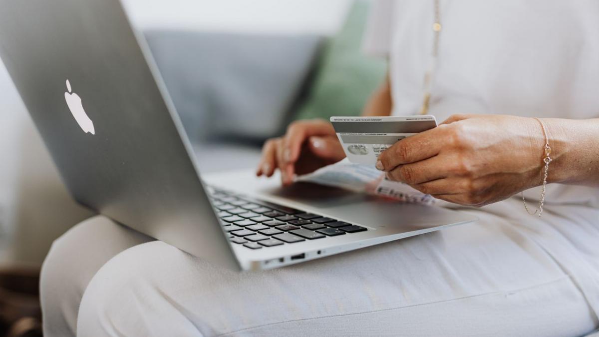 Persoană care accesează un credit nebancar online cu laptop și card bancar