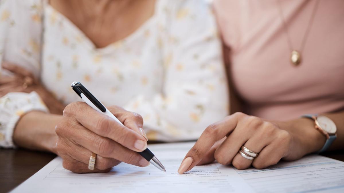 o femeie care ii arata alteia unde sa semneze pe un contract