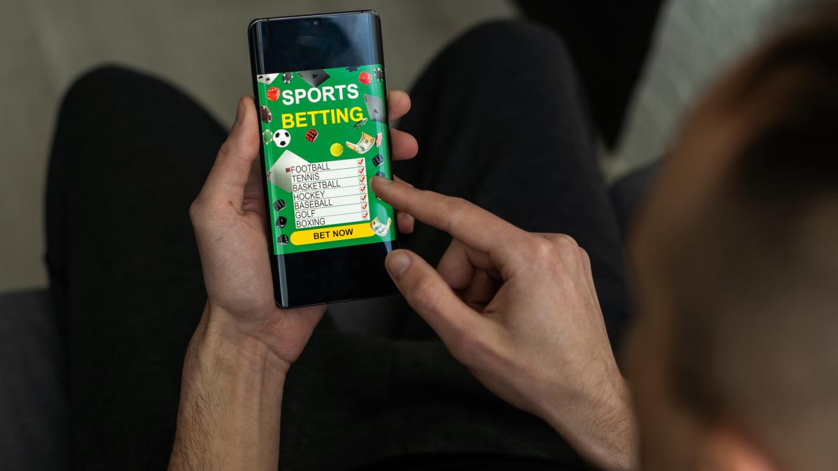 bărbat pe telefon punând pariuri sportive 