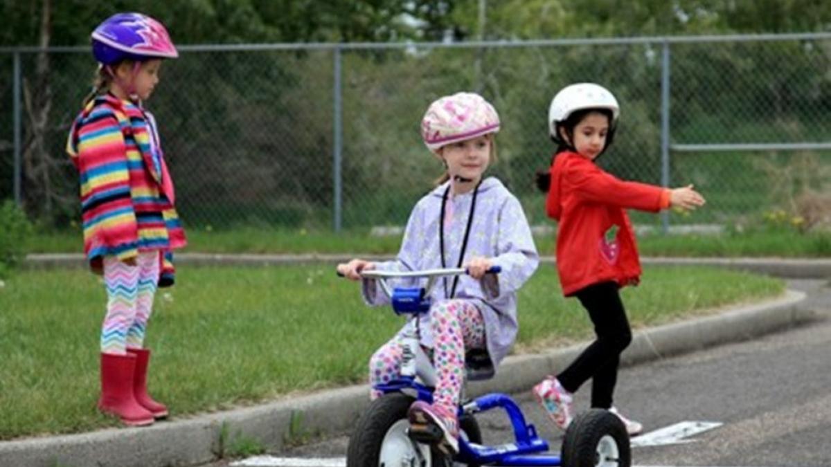 3 fetițe mici jucându-se afara cu bicicleta