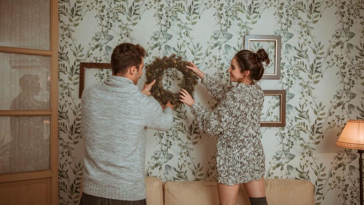 o femeie si un bărbat decorând o camera cu tapet 