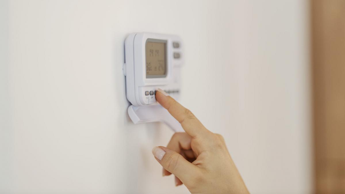 mana de femeie care regleaza temperatura la termostat