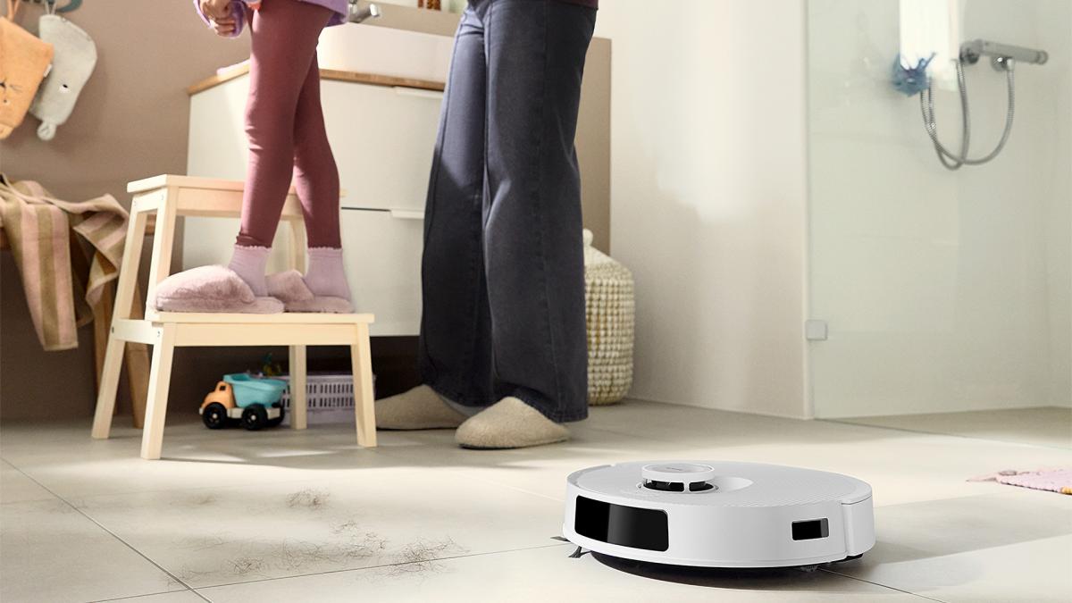 aspirator robot pe covor într-o camera cu un adult si un copil 