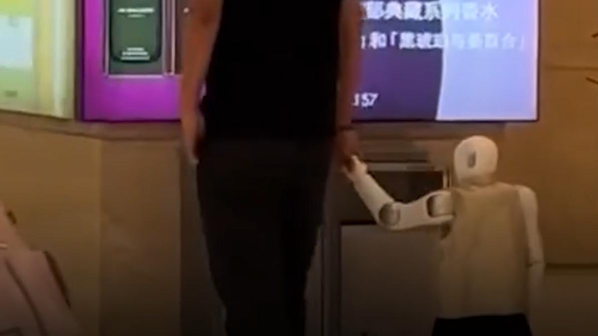 un barbat plimba de mana un robot umanoid printr un mall din china ca pe propriul copil
