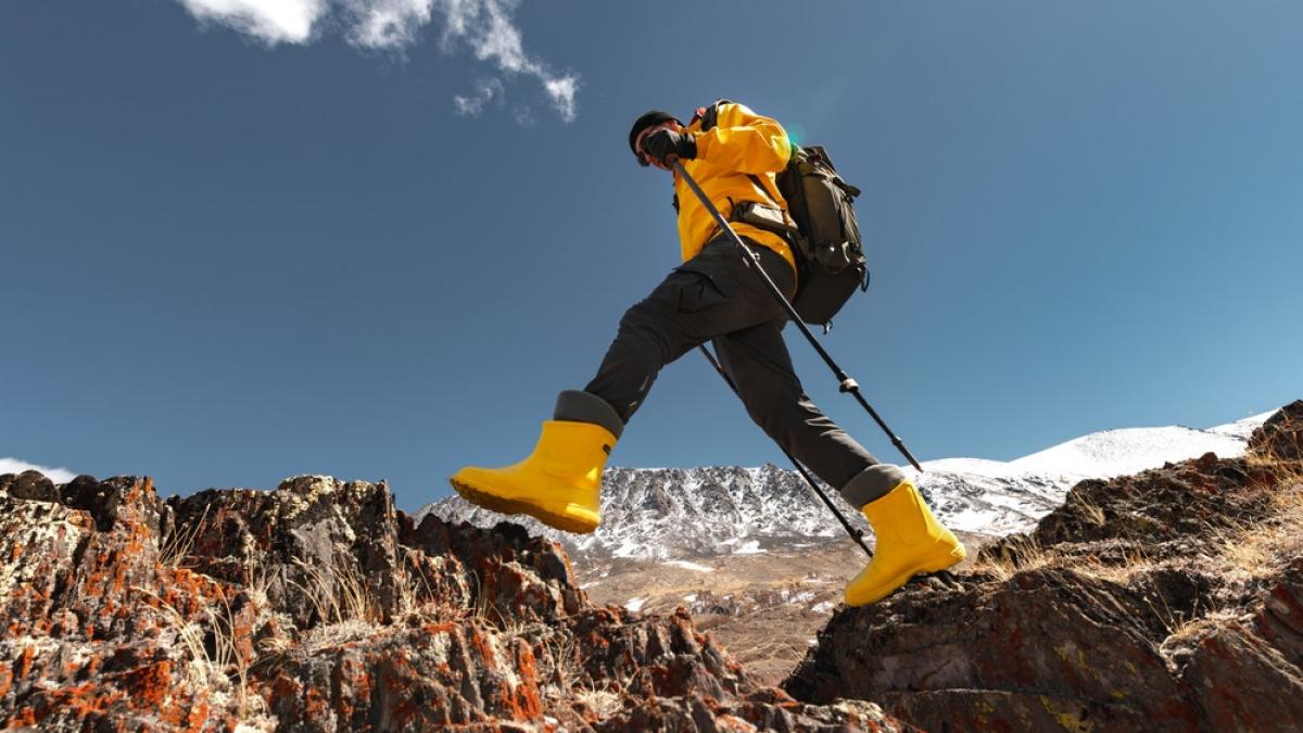 barbat imbracat corespunzător făcând trekking pe un munte 
