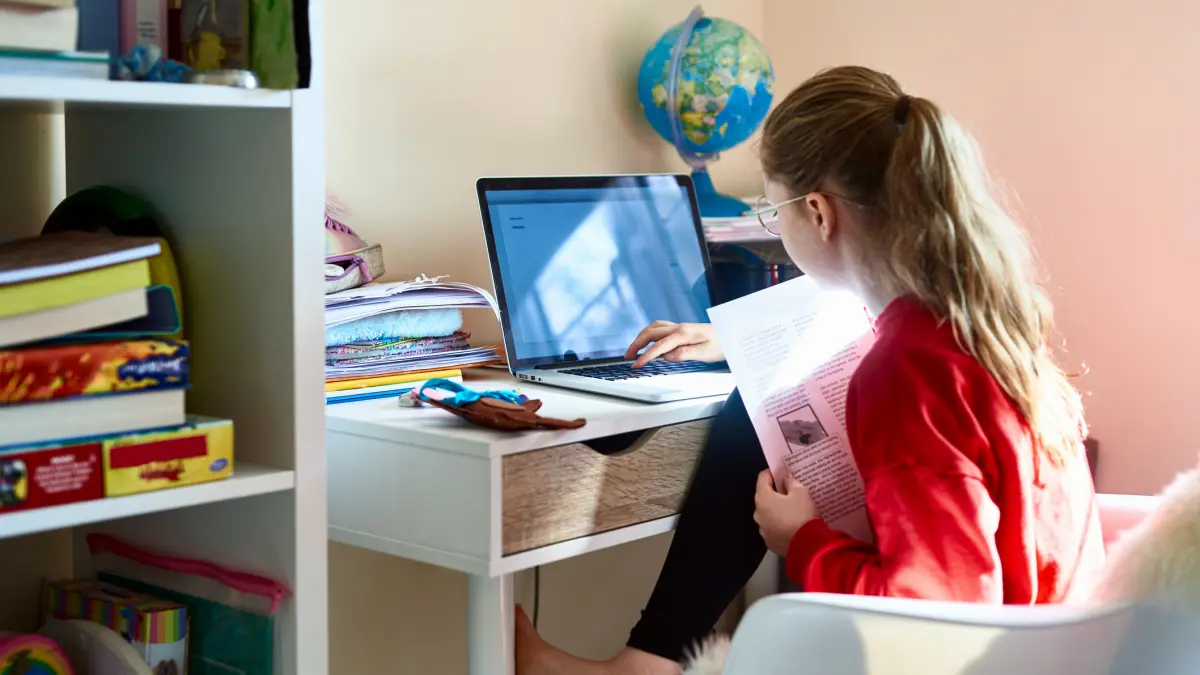 poza in care apare o eleva care invata la biroul de acasa, iar in fata ei este un laptop