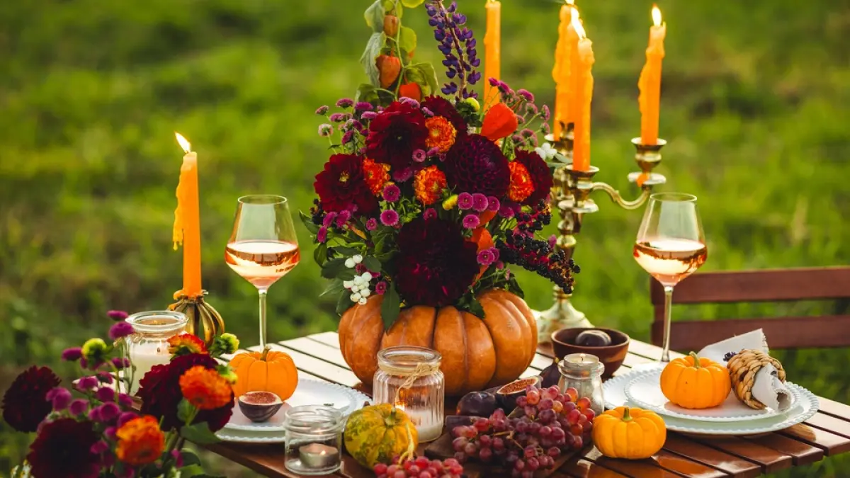 masa romantică in aer liber decorata cu flori si lumânări si doua sticle de vin 