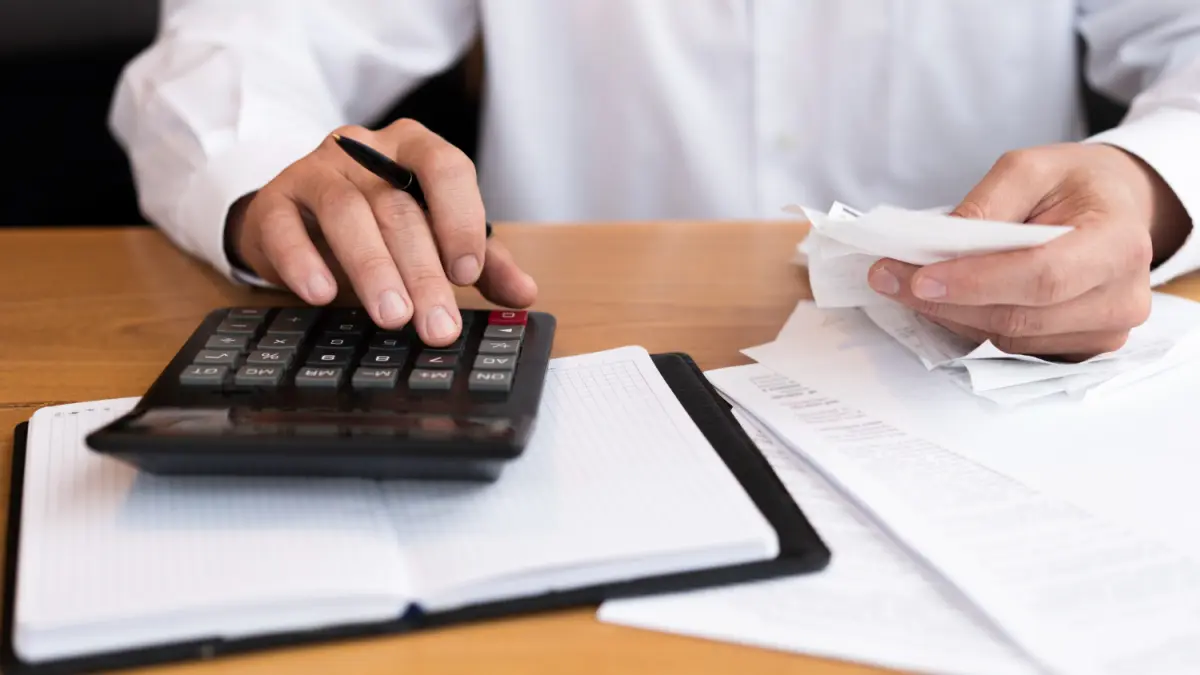 barbat la birou cu bonuri fiscale într-o mana calculând ceva 