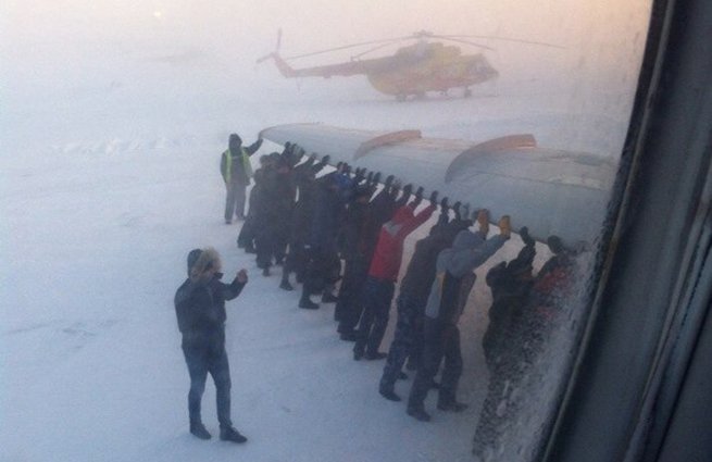 Numai în RUSIA! Pasageri ruşi, nevoiţi să împingă un avion al cărui tren de aterizare îngheţase. Afară erau -52 de grade Celsius