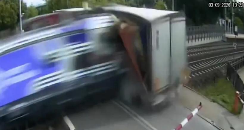 VIDEO Un camion a fost blocat pe șine de bariere, dar șoferul n-a vrut să le spargă și nu a mai reușit să evite trenul 