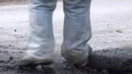Drumarii tasează cu picioarele asfaltul pus în gropi