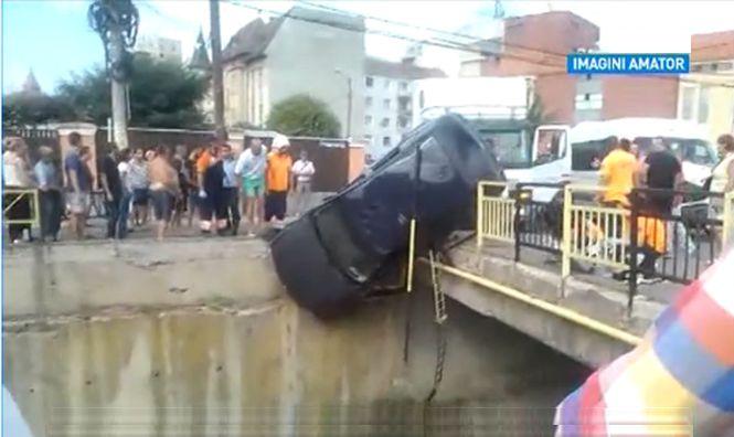 Maşină suspendată pe pod, după ce a fost lovită de un microbuz