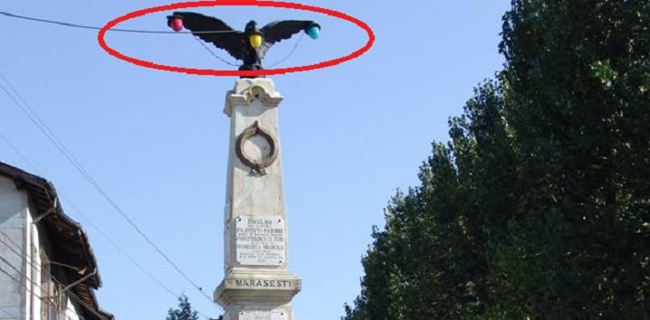 Un vultur cu un bec în cioc. Un monument ridicat în memoria eroilor, „decorat” cu lămpi de iluminat public