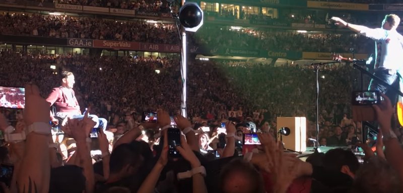 Fan Coldplay în scaun cu rotile, purtat pe brațe de mulțime până pe scenă - VIDEO