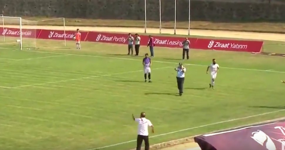 Un poliţist care vorbea la telefon a intrat din greşeală pe teren în timpul unui meci de fotbal - VIDEO