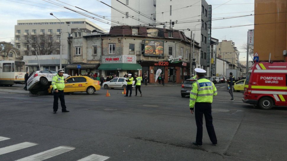  Primele imagini de la accidentul grav din Capitală unde o maşină de poliţie s-a răsturnat peste un taxi 