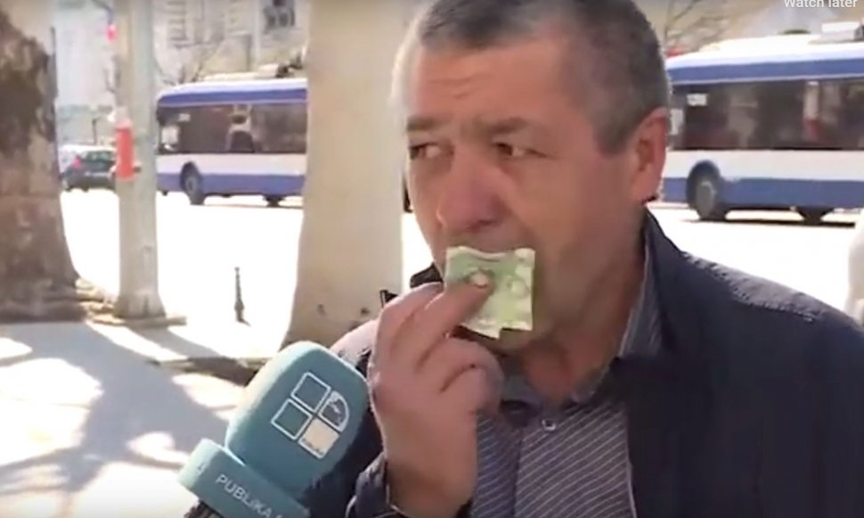 Un bărbat bagă în gură o bancnotă ca să demonstreze că ”pe bani nu-s bacterii”