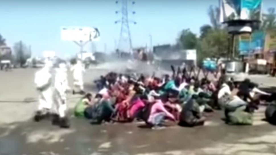 Muncitori stropiți la grămadă cu dezinfectant pentru autobuze, în India