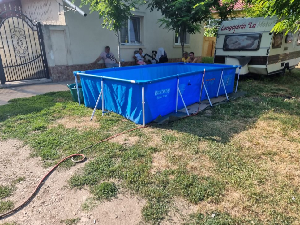 O familie din Timiș și-a făcut piscină în fața casei cu apă adusă cu furtunul din fântâna publică