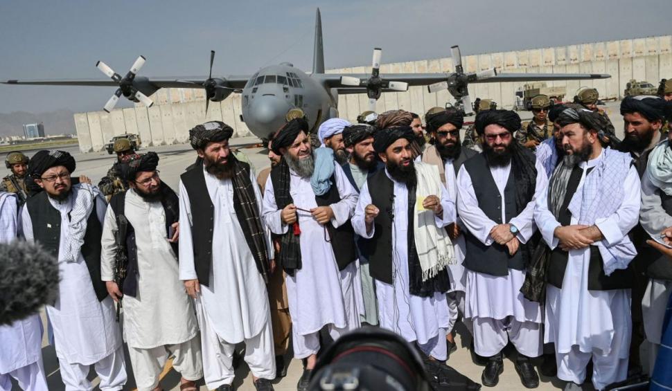 Imagine-document după retragerea SUA din Afganistan: purtătorul de cuvânt al talibanilor, pe aeroportul din Kabul, cu un avion american în spate