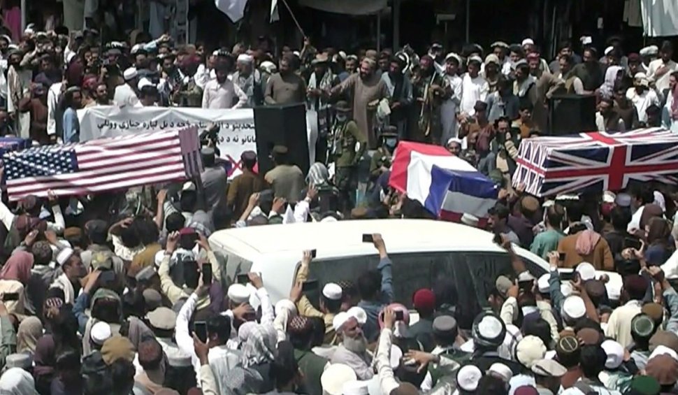 Sicrie învelite în steaguri americane, britanice și franceze, conduse de mulțime pe străzile unui oraș din Afganistan
