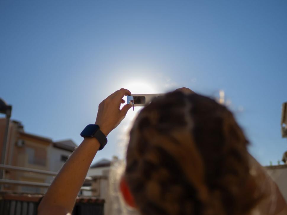 o femeie se uita la eclipsa de soare prin ochelari speciali