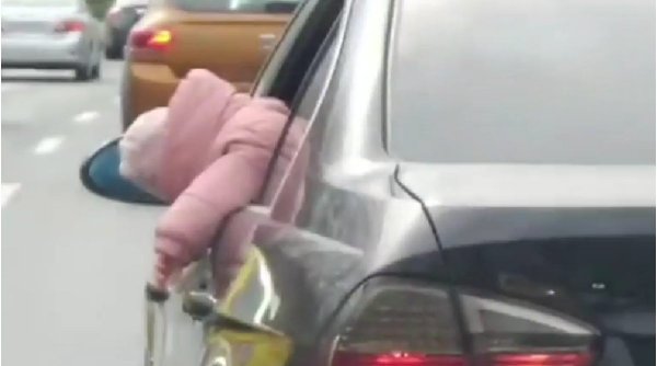 Copil ieșit mai mult de jumătate pe geamul mașinii, filmat în traficul din București. Poliția este în alertă 
