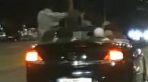 Momentul în care un şofer teribilist ia mâinile de pe volan şi se ridică in picioare, din decapotabilă